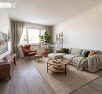 Nappali egy háromszobás lakásban nagy kanapéval, fotellel és fa dekorációjú padlóval.