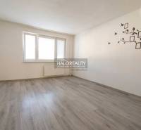 Szoba egy háromszobás lakásban fa dekoros padlóval és fehér falakkal.