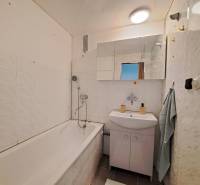 Fürdőszoba egy kétszobás lakásban káddal, mosdóval és tükörrel.