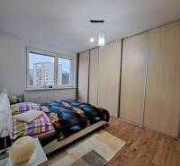 Hálószoba egy kétszobás lakásban fa dekor padlóval és nagy beépített szekrénnyel.