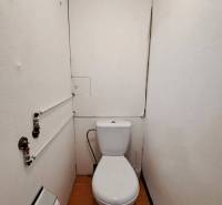 Fürdőszoba WC-vel és fa dekoros padlóval egy kétszobás lakásban.