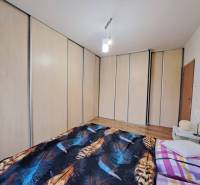 Hálószoba nagy beépített szekrénnyel és ággyal egy kétszobás lakásban.