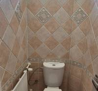 Fürdőszoba WC-vel egy háromszobás lakásban, csempézett falak és ablak.