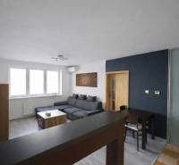 Nappali egy háromszobás lakásban sarokkanapéval és fa dekorációjú padlóval.