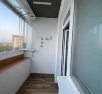 Üvegezett loggia egy 3 szobás lakásban, fa hatású padlóval.