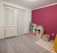 Gyerekszoba egy háromszobás lakásban, fa dekoros padlóval és színes falakkal.