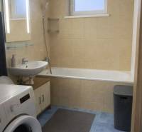 Fürdőszoba káddal, mosdóval és mosógéppel egy háromszobás lakásban, kék csempékkel.