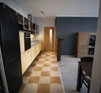 Konyha egy 3 szobás lakásban konyhabútorral és étkezőasztallal, padló csempével.