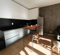 Konyha egy kétszobás lakásban sötét fallal és fa dekorációjú padlóval.