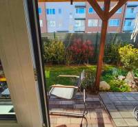 Kert terasszal és székekkel a kétszobás lakásban, kilátás az üvegajtón keresztül.