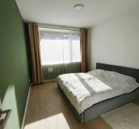 Hálószoba egy kétszobás lakásban, ággyal és ablakkal, fa hatású padlóval.