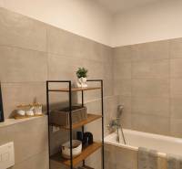 Fürdőszoba káddal és polccal egy kétszobás lakásban, dekoráció és tároló kosarak.