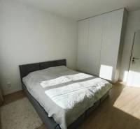 Hálószoba egy kétszobás lakásban ággyal, beépített szekrénnyel, fa dekoros padlóval.