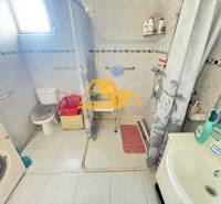 Családi ház fürdőszobája mosógéppel, zuhanyzóval és WC-vel.