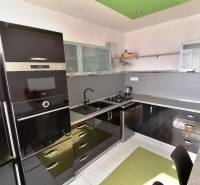 Moderná kuchyňa s čiernymi skrinkami a bielej podlahy v 3-izbovom byte.