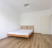 Hálószoba ággyal és fa dekorációjú padlóval egy háromszobás lakásban.