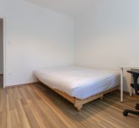 Hálószoba egy háromszobás lakásban, ággyal, íróasztallal és fa dekorációjú padlóval.