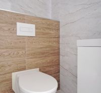 Családi ház fürdőszobájában található WC márvány- és fa burkolatokkal.