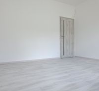 Üres szoba fa mintázatú padlóval és zárt ajtókkal egy családi házban.