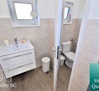 Fürdőszoba mosdóval, WC-vel és fa dekorációjú padlóval egy családi házban.