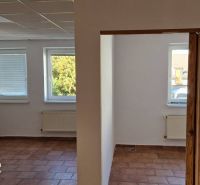 Családi ház belső tere terrakotta padlóval, fehér falakkal és ablakok alatti radiátorokkal.