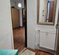 Egy családi ház helyisége fa mintázatú padlóval, tükörrel és radiátorral.