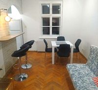 Étkező sarok fehér asztallal, szürke székekkel és fa dekorációjú padlóval egy kétszobás lakásban.