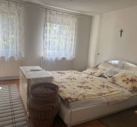 Hálószoba a házban ággyal, szőnyeggel, fehér komóddal és függönyökkel, fa dekorációjú padlóval.