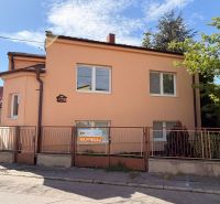 Családi ház a Pöstyéni Malom utcában fehér ablakokkal, narancssárga homlokzattal és kerítéssel.