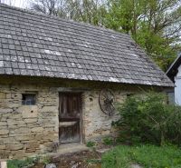 Kőből épült pajta egy családi ház mellett Bukovecben, faajtókkal és cseréptetővel.