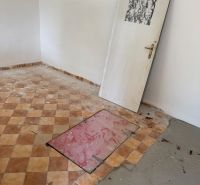 Szoba egy faházban cseréppadlóval és zsanér nélküli ajtókkal.