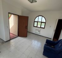 Izba egy házban teraszajtóval, csempézett padlóval és sötétkék fotellel.
