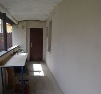 Folyosó fehér falakkal, repedések a padlón, asztal, ajtó egy családi házban.