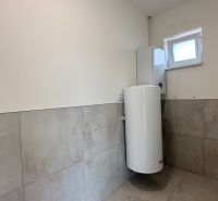 Fürdőszoba egy családi házban, csempézett falakkal és bojlerrel.