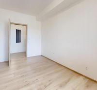 Fehér falú és fa mintázatú padlójú szoba egy kétszobás lakásban.