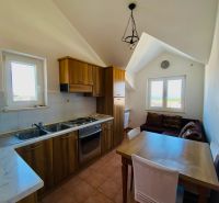 Konyha fa dekorációval, étkezőasztallal és kanapéval egy üdülő apartmanban.