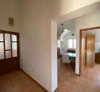Folyosó egy üdülő apartmanban kerámia padlóval, étkező sarok és szoba a háttérben.