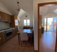 Nyaraló apartman konyhája fa szekrényekkel és kilátással a tengerre.