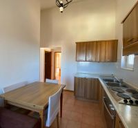 Nyaraló apartman konyhája fa szekrényekkel és étkezőasztallal.