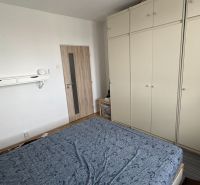 Hálószoba nagy gardróbszekrénnyel és fa dekorációjú padlóval egy kétszobás lakásban.