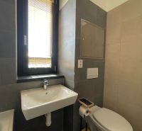 Fürdőszoba mosdóval, WC-vel és ablakkal egy kétszobás lakásban.