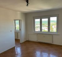 Világos szoba három ablakkal és fa dekorációjú padlóval egy kétszobás lakásban.