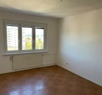 Kétszobás lakás szobája fa mintázatú padlóval és nagy ablakkal.