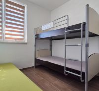 Emeletes ágy és zöld kanapé egy családi házban, fa dekorációs padlóval.