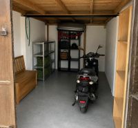 Garázs motorkával, fa mennyezettel és tároló polcokkal.