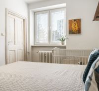 Hálószoba egy háromszobás lakásban ággyal, növénnyel és dekoratív képpel a falon.