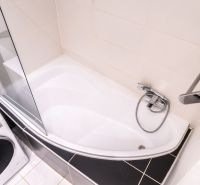 Fürdőszoba káddal, zuhanyfallal és mosógéppel egy háromszobás lakásban.