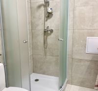 Zuhanykabin és WC az egyszobás lakás fürdőszobájában csempékkel.