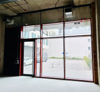 Obchodhelyiségek nagy üvegajtókkal és nyers betonfalakkal.
