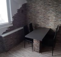 Étkező sarok asztallal és székekkel a kétszobás lakásban, kőfal.